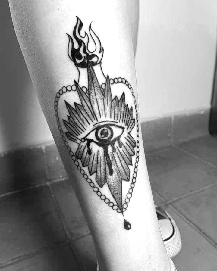 Tatuaje de un ojo dentro de un corazon en la pierna