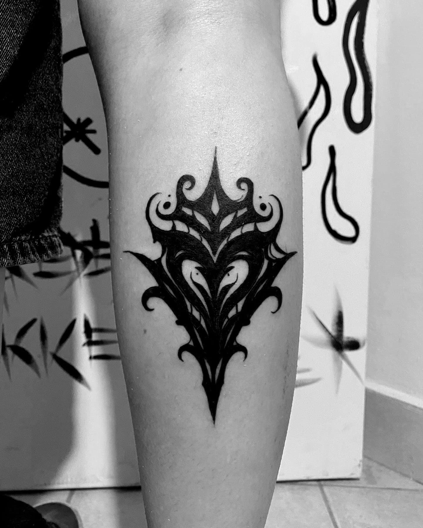 Tatuaje de corazon con estilo neotribal y relleno negro en la pierna