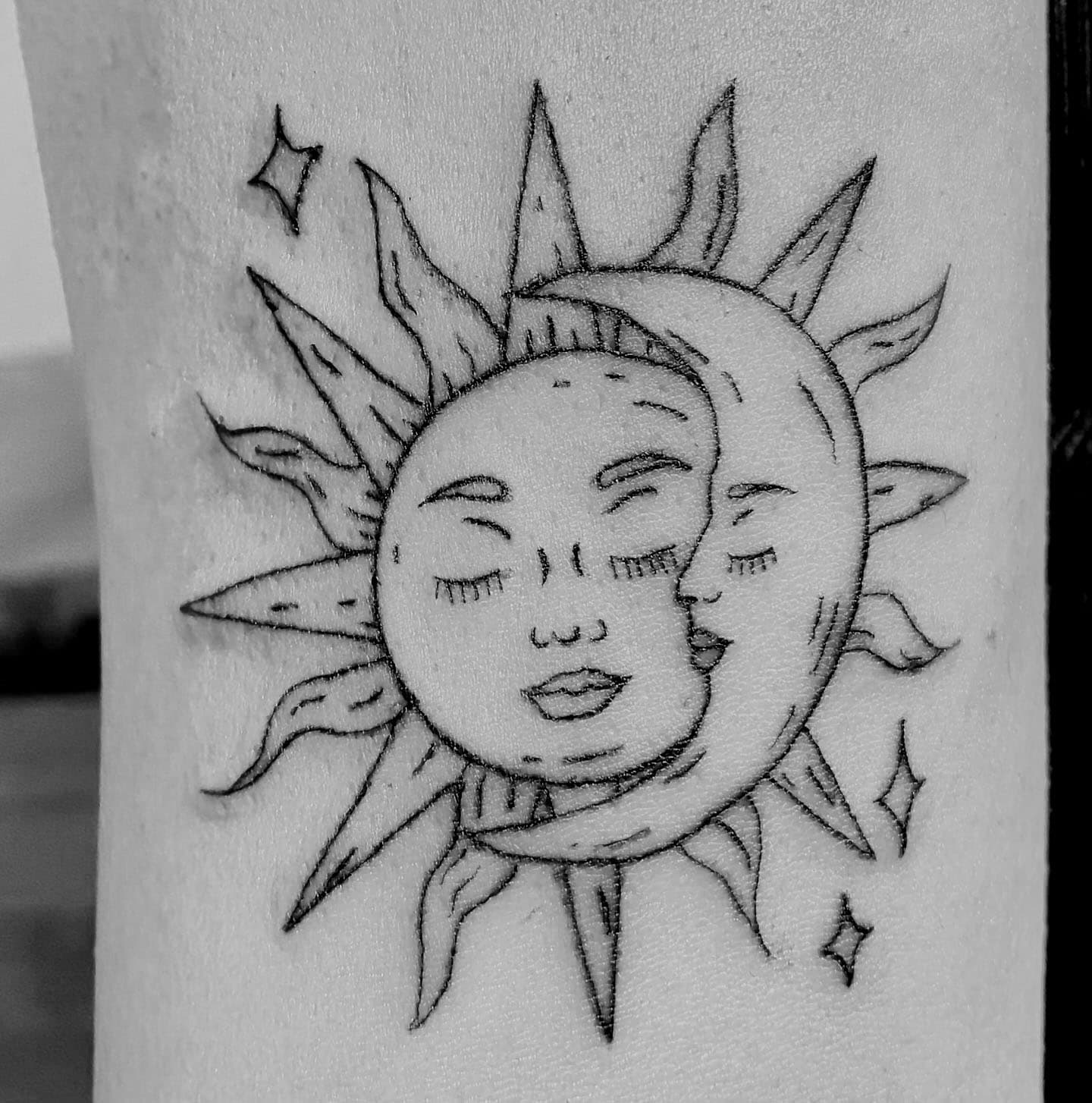 Tatuaje de un sol y una luna con estilo fine line en el brazo