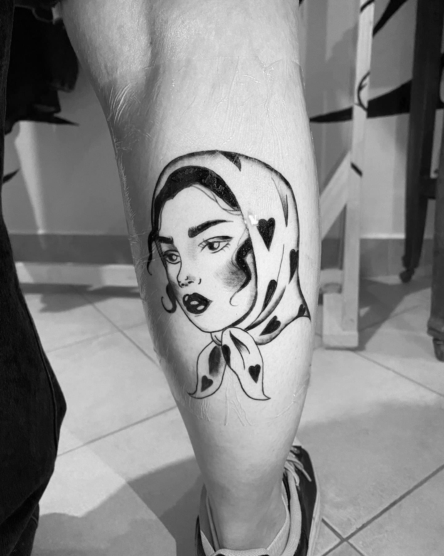 Tatuaje del rostro de una mujer en la pantorrilla